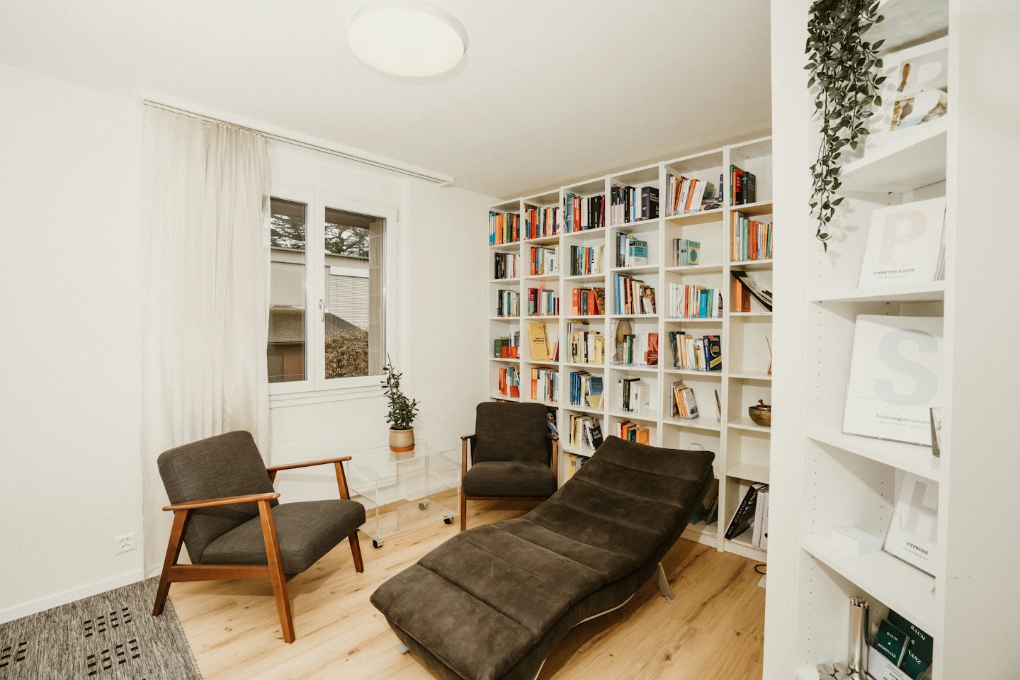 Accogliente studio di terapia con poltrone, chaise longue e librerie.